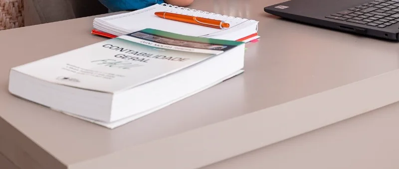 Mesa de trabalho com livro de contabilidade geral e anotações